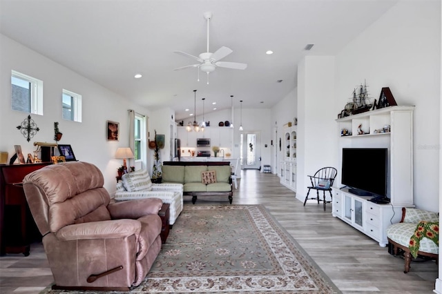 living room featuring vaulted ceiling, light hardwood / wood-style flooring, and ceiling fan