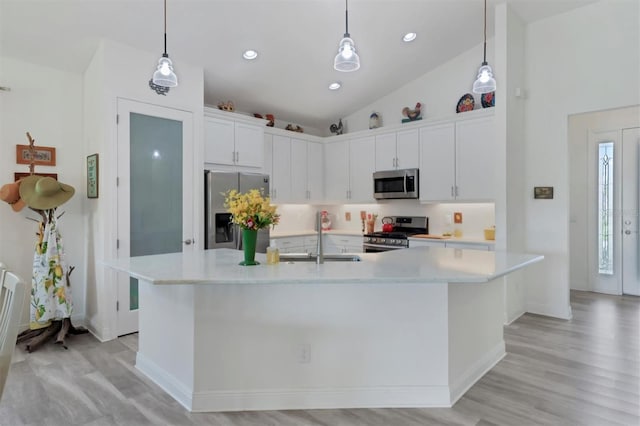 kitchen with white cabinetry, light wood-type flooring, stainless steel appliances, a spacious island, and sink