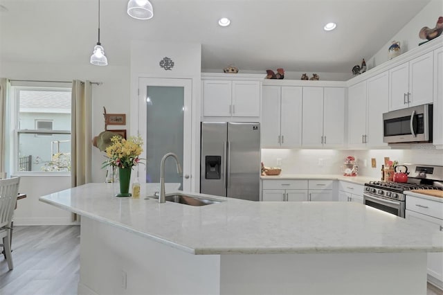 kitchen with appliances with stainless steel finishes, light hardwood / wood-style flooring, sink, backsplash, and light stone countertops