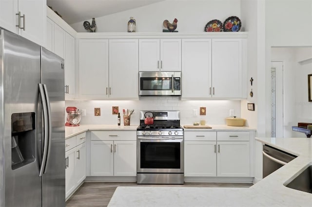 kitchen featuring white cabinetry, lofted ceiling, light wood-type flooring, and stainless steel appliances