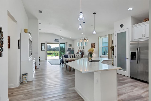 kitchen featuring stainless steel fridge with ice dispenser, an island with sink, light wood-type flooring, sink, and lofted ceiling