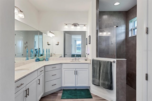 bathroom featuring dual vanity, tiled shower, and hardwood / wood-style flooring