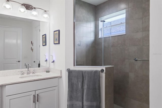 bathroom featuring tiled shower and vanity