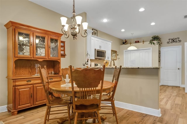 dining area featuring light wood-type flooring, sink, and a chandelier