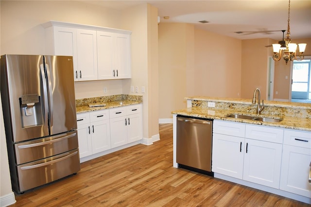 kitchen featuring pendant lighting, sink, light hardwood / wood-style flooring, white cabinetry, and stainless steel appliances