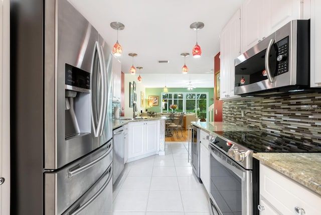 kitchen featuring decorative backsplash, light hardwood / wood-style flooring, light stone counters, white cabinets, and stainless steel appliances