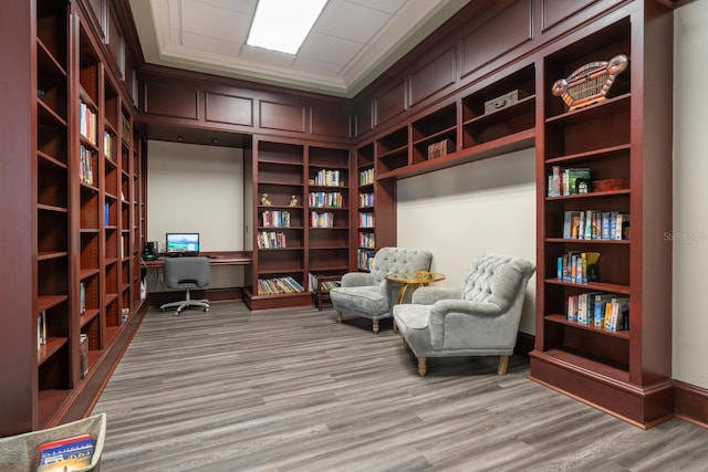 sitting room featuring light hardwood / wood-style flooring, built in features, and ornamental molding