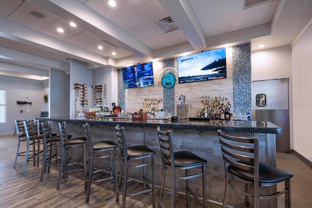 bar featuring dark stone countertops and wood-type flooring