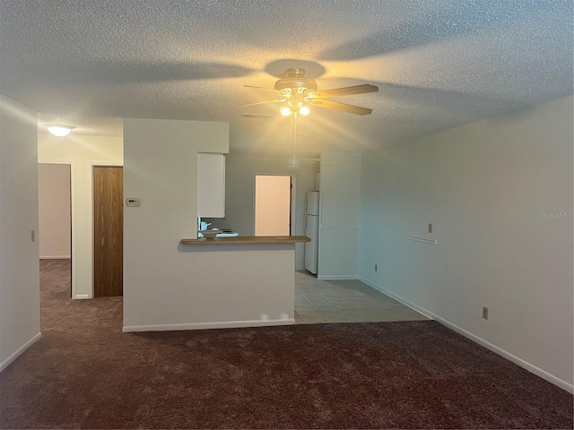 unfurnished living room featuring light carpet, ceiling fan, and a textured ceiling