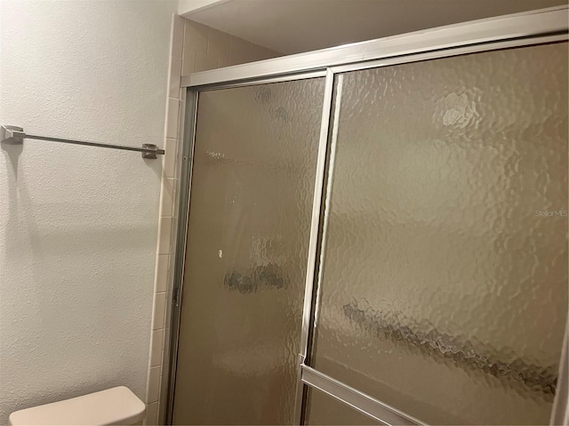 bathroom with a shower with door and toilet