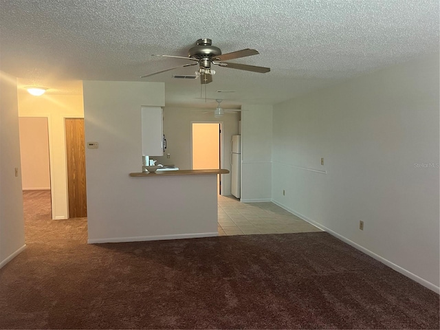 unfurnished living room featuring light carpet, ceiling fan, and a textured ceiling