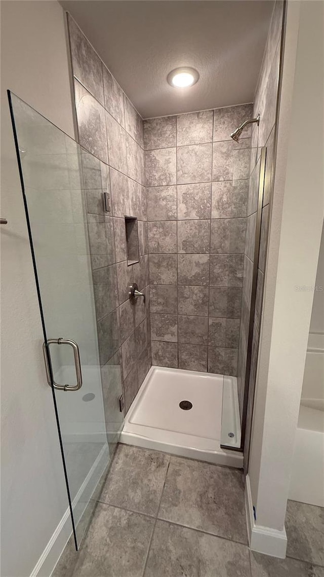 bathroom with tile patterned floors and a shower with door