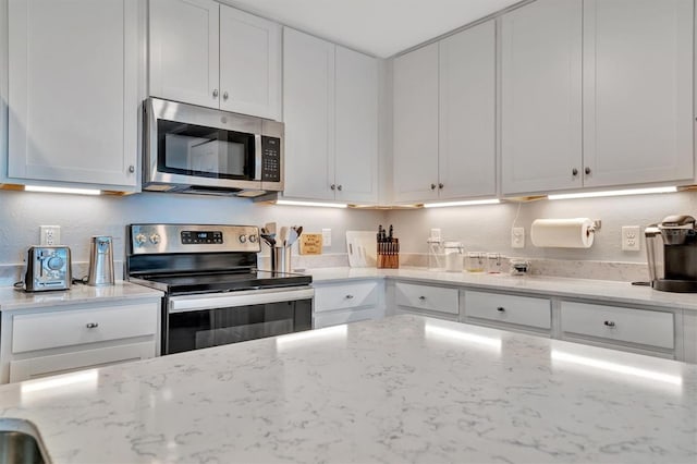 kitchen with light stone counters, white cabinets, and appliances with stainless steel finishes