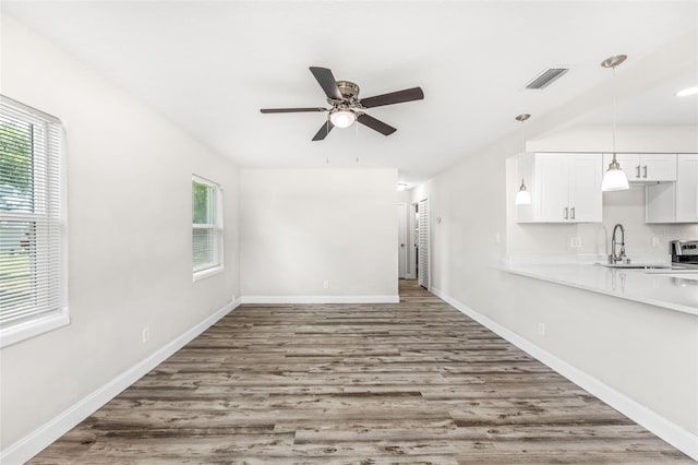 unfurnished living room featuring wood-type flooring, sink, and ceiling fan