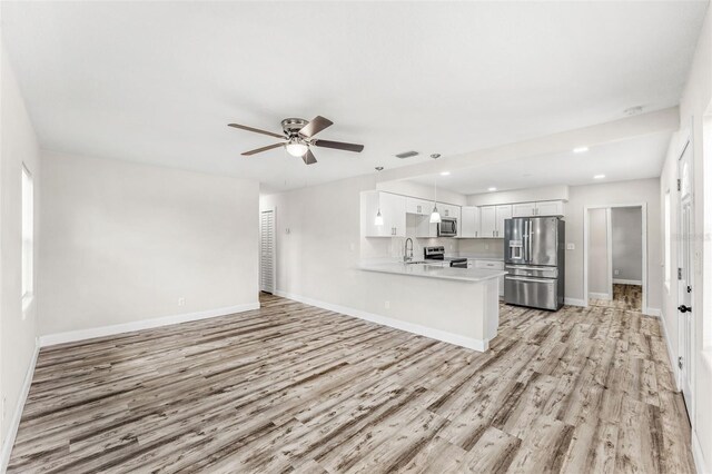 kitchen with appliances with stainless steel finishes, white cabinets, kitchen peninsula, light hardwood / wood-style floors, and ceiling fan