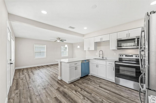 kitchen with ceiling fan, sink, light hardwood / wood-style floors, appliances with stainless steel finishes, and kitchen peninsula