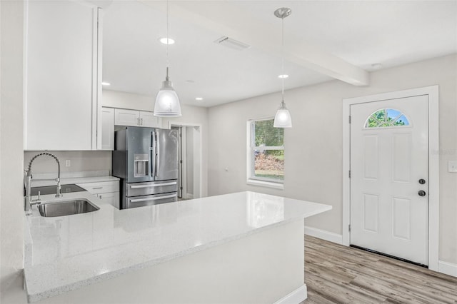 kitchen with stainless steel fridge, sink, hanging light fixtures, and plenty of natural light