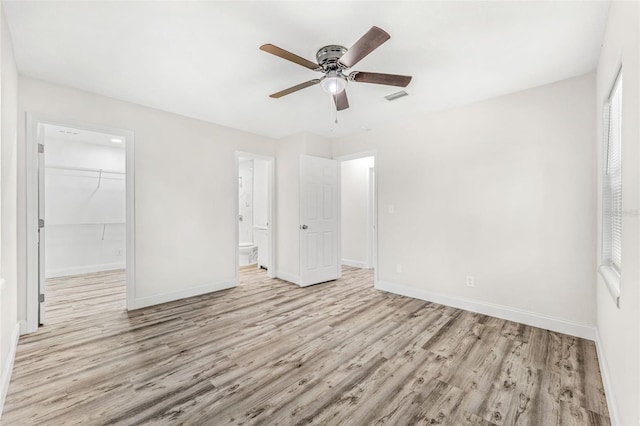 unfurnished bedroom featuring light hardwood / wood-style floors, a closet, ensuite bath, and ceiling fan