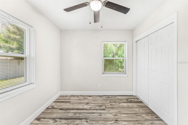 unfurnished bedroom featuring wood-type flooring, multiple windows, a closet, and ceiling fan