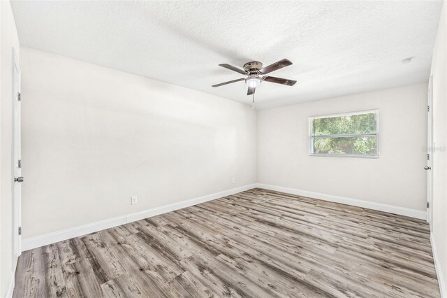 empty room with a textured ceiling, light wood-type flooring, and ceiling fan