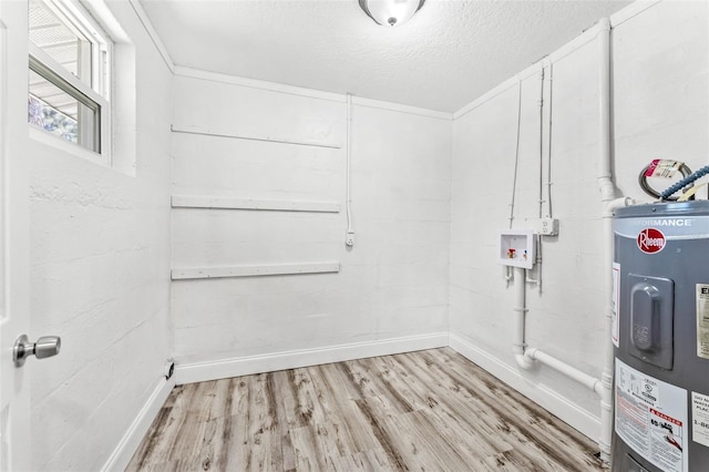 washroom with electric water heater, hookup for a washing machine, a textured ceiling, and light wood-type flooring