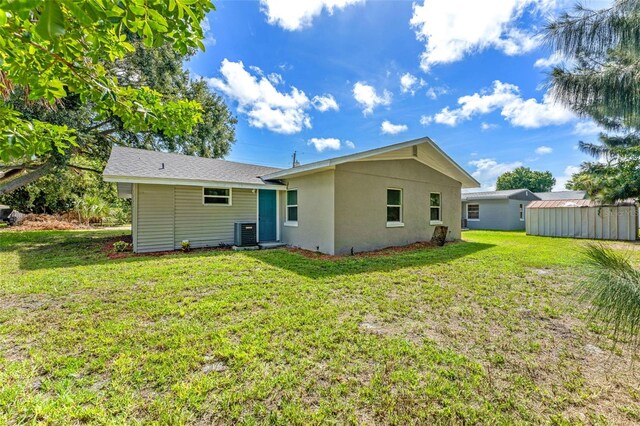 rear view of house with a storage shed, central AC, and a lawn