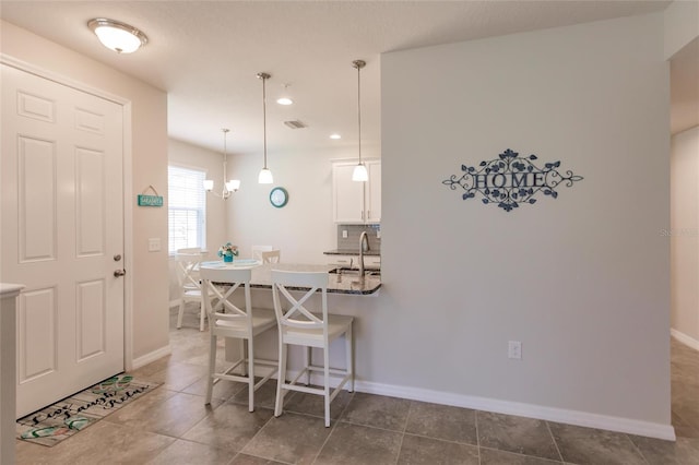 tiled dining room featuring sink and a notable chandelier