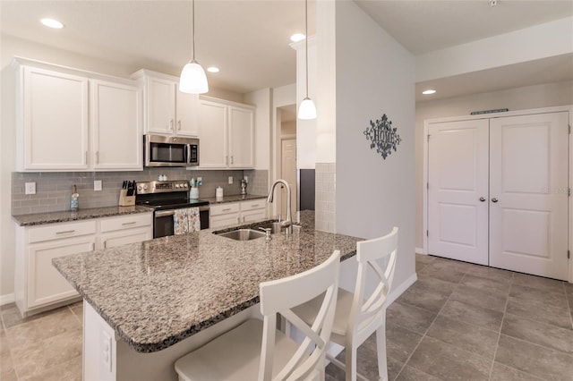 kitchen with stainless steel appliances, white cabinetry, sink, and decorative light fixtures