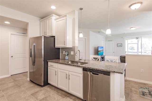 kitchen featuring decorative light fixtures, sink, dark stone countertops, white cabinets, and stainless steel appliances