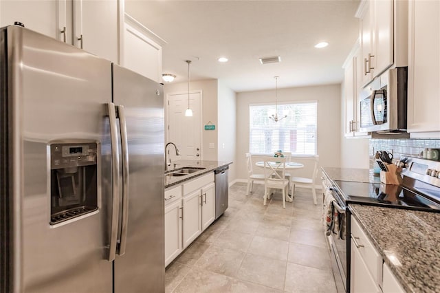 kitchen featuring stone countertops, decorative light fixtures, white cabinets, stainless steel appliances, and backsplash