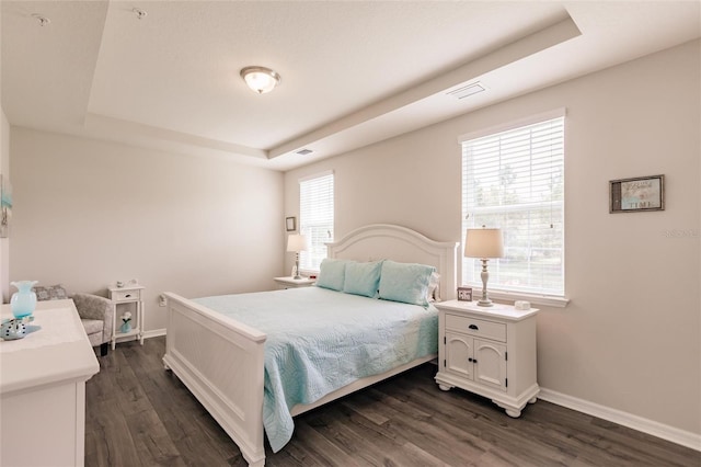 bedroom featuring dark wood-type flooring and a tray ceiling