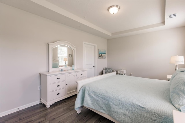 bedroom with dark hardwood / wood-style floors and a raised ceiling