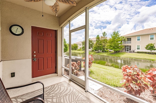 sunroom with a water view and ceiling fan