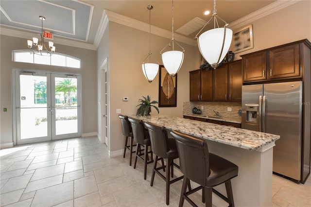 kitchen featuring decorative light fixtures, stainless steel fridge, decorative backsplash, ornamental molding, and light stone counters