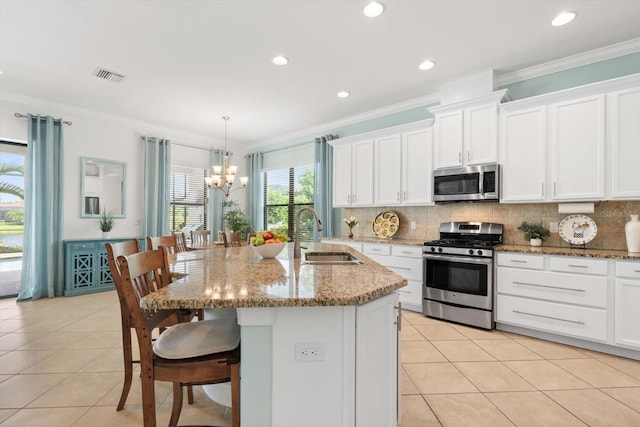 kitchen featuring decorative light fixtures, stainless steel appliances, a chandelier, sink, and a kitchen island with sink