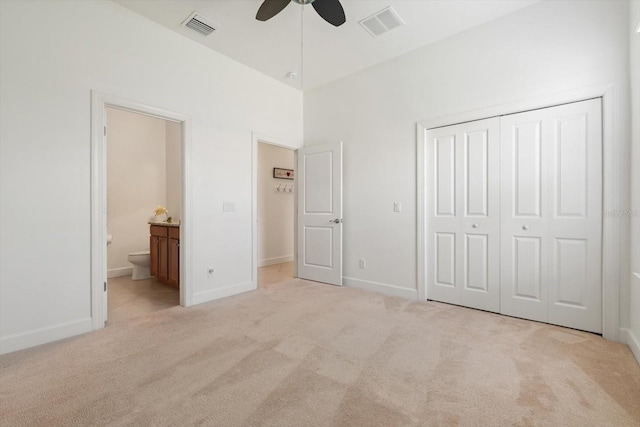 unfurnished bedroom with light colored carpet, ceiling fan, a closet, and ensuite bathroom