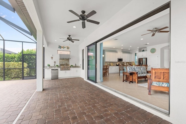 view of patio with glass enclosure, ceiling fan, and an outdoor kitchen