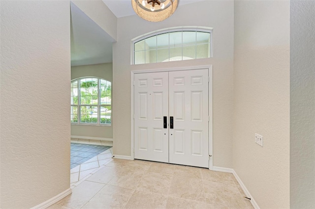 entryway with light tile patterned flooring and an inviting chandelier