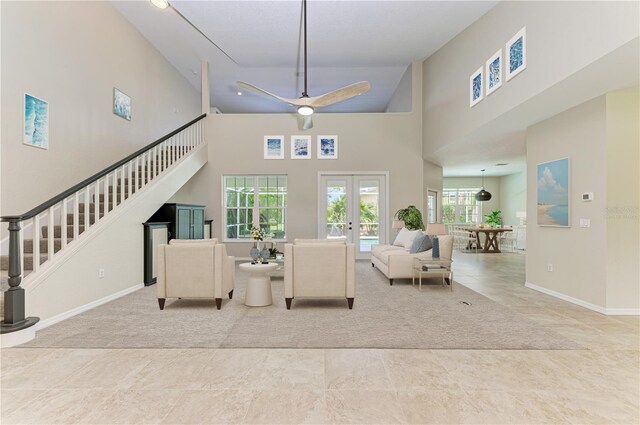 tiled living room with a high ceiling, ceiling fan, and french doors