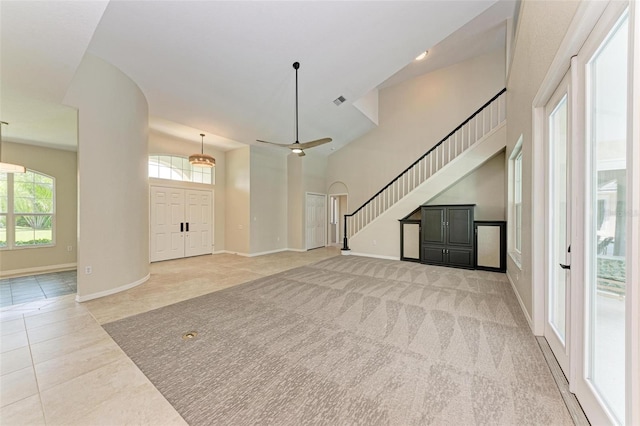 unfurnished living room with high vaulted ceiling and light tile patterned floors