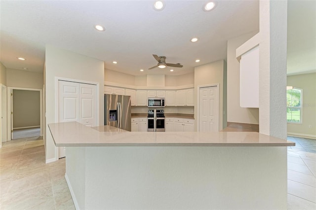 kitchen with appliances with stainless steel finishes, white cabinetry, kitchen peninsula, ceiling fan, and light tile patterned flooring