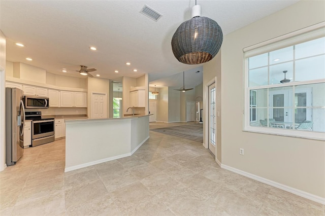 kitchen featuring appliances with stainless steel finishes, white cabinets, ceiling fan, pendant lighting, and sink