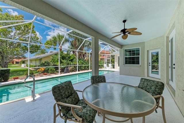 view of swimming pool featuring glass enclosure, a patio area, and ceiling fan