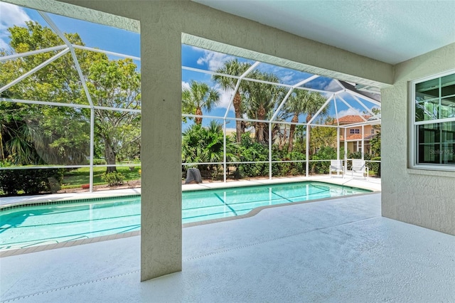 view of pool featuring glass enclosure and a patio area