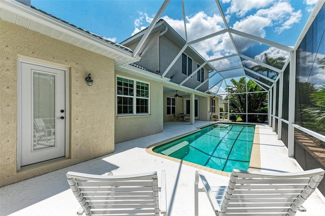 view of pool featuring glass enclosure, ceiling fan, and a patio area