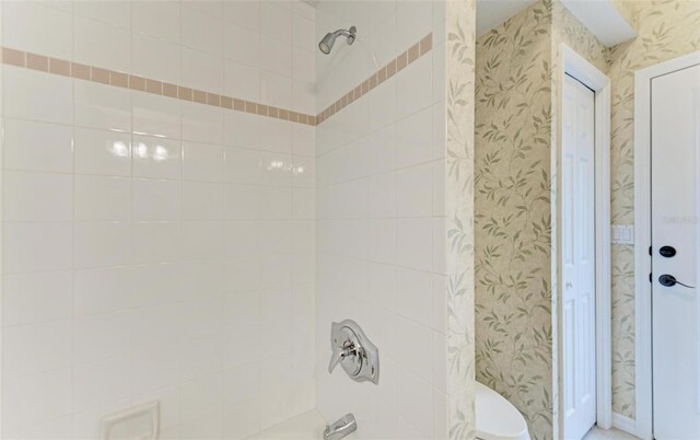 bathroom with a tile shower and toilet