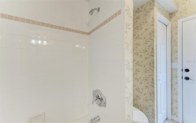 bathroom with toilet and tiled shower / bath combo