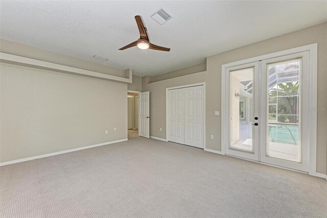 unfurnished bedroom featuring ceiling fan, light carpet, a closet, french doors, and access to exterior