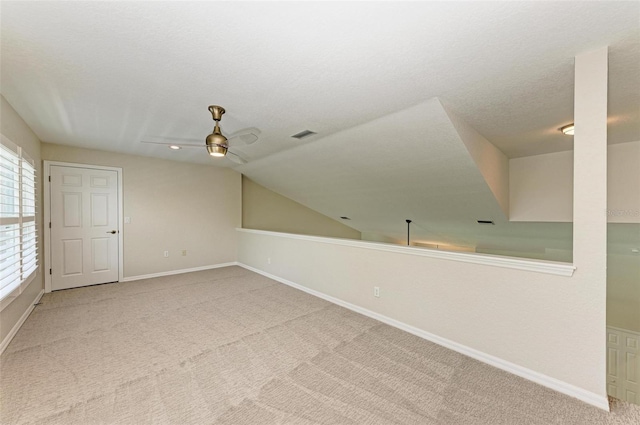 additional living space with a textured ceiling, lofted ceiling, carpet flooring, and ceiling fan