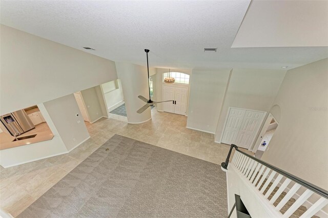 carpeted living room featuring high vaulted ceiling and a textured ceiling